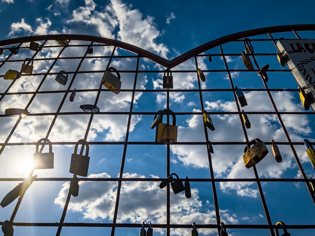 Zero Trust in der Private Cloud | © by wirestock Low angle shot of a heart-shaped fence with padlocks on a cloudy sky background | © by wirestock